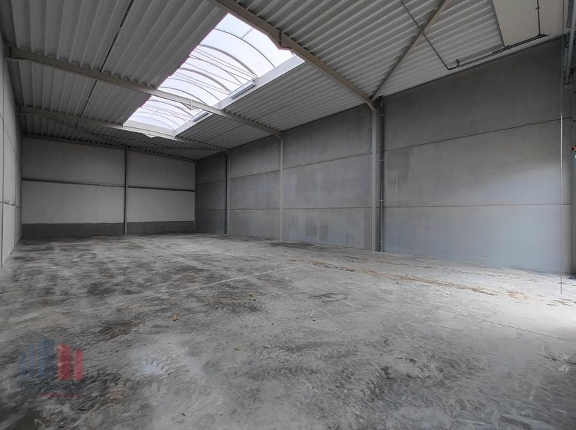 De casco loods van 440 m² heeft een vrije hoogte van 6 m en is opgebouwd uit een staalstructuur met betonplint in combinatie met geïsoleerde sandwichp