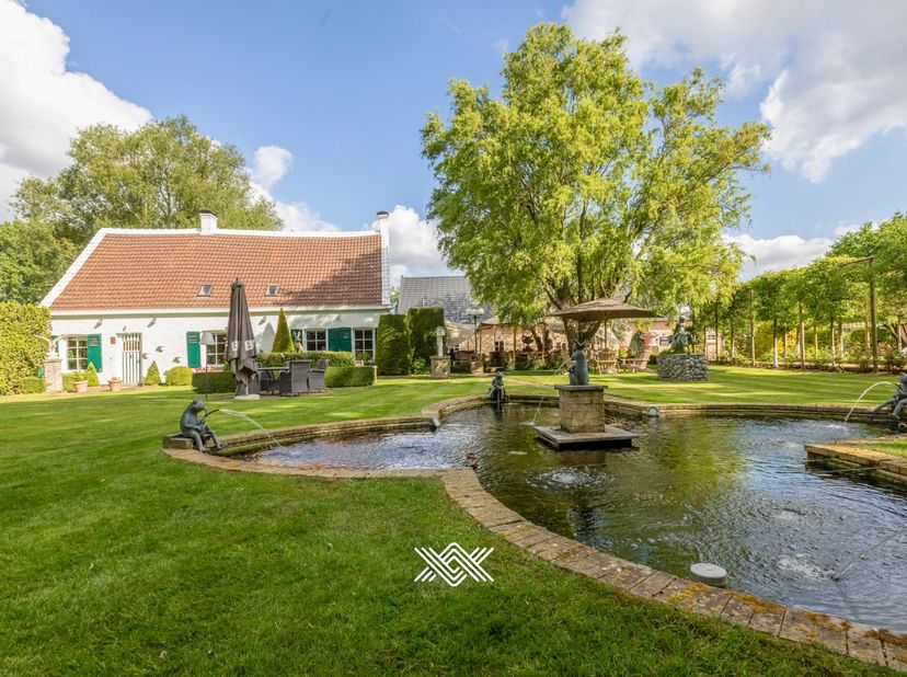 Verscholen tussen het groen, met liefst 110 meter oever langs het water, bevindt zich dit rustig gelegen landhuis met bedrijfsgebouw in Lievegem. Deze