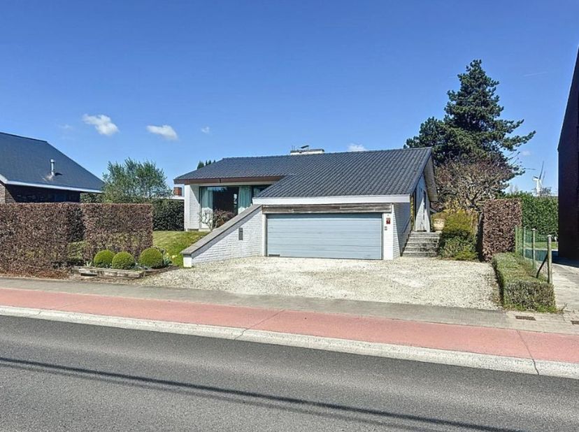 Centraal gelegen villa op een ruim perceel, bestaande uit een inkomhal met vestiaire en afzonderlijk toilet, bureel/slaapkamer, lichtrijke leefruimte