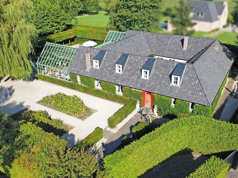 Achter een afgesloten toegangspoort met prachtig aangelegde binnenkoer bevindt zich deze charmante vierkantshoeve, welke door de jaren heen een volled