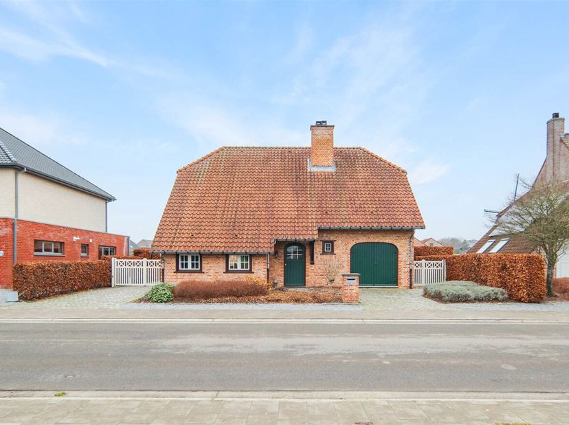 Bij binnenkomst betreedt u de inkomhal, die toegang biedt tot de verschillende ruimtes in de woning. Aan de linkerkant bevindt zich de L-vormige woonk