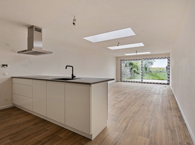 Ruime nieuwbouwwoning bestaande uit hal met apart toilet. Gezellige living met open en volledig geïnstalleerde keuken met schuifraam naar tuin en terr