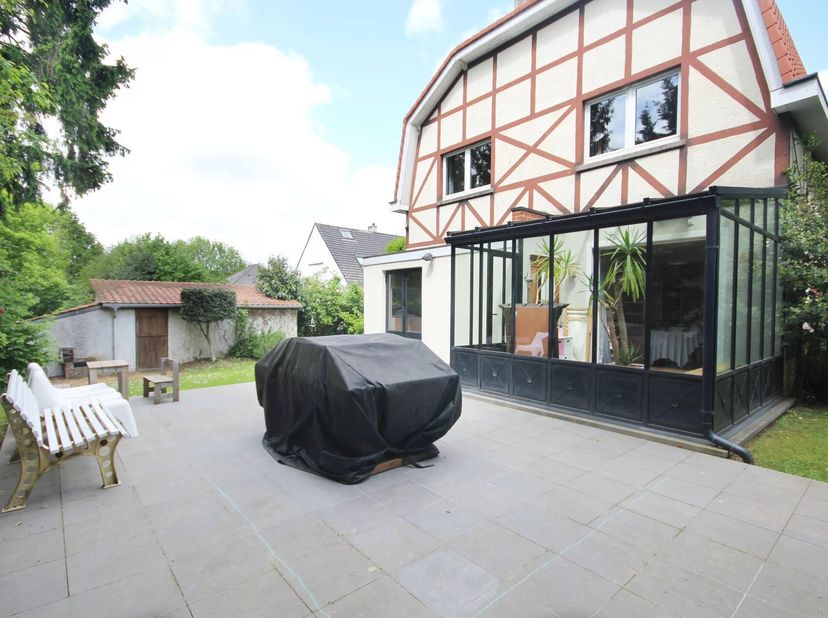 Située dans un quartier résidentiel calme et verdoyant, à proximité des parcs et des écoles (notamment le Lycée Français), cette villa de style norman