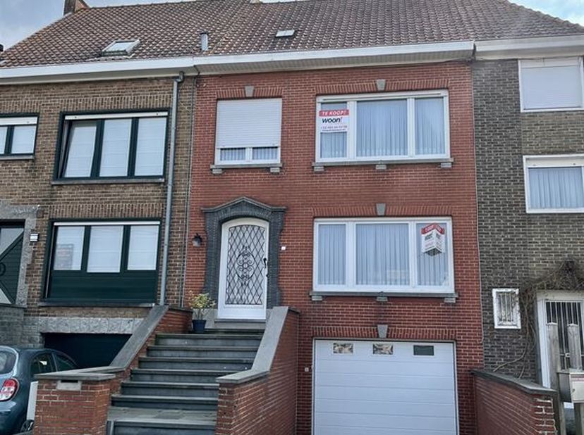 Gezellige stadswoning met garage en tuin. Deze woning omvat een inkomhal, dubbele beglaasde deur naar de woonkamer met eet-en zithoek, veranda met toe