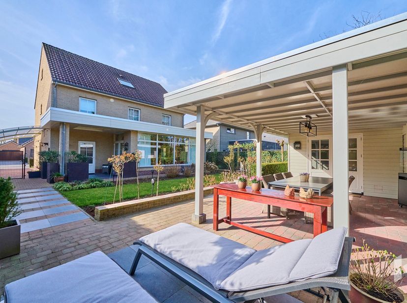 Prachtige woning (265 m²) met een lichtrijke woonkamer, uitgerust met gashaard, die overloopt naar de veranda met zicht en toegang tot de fraaie tuin.