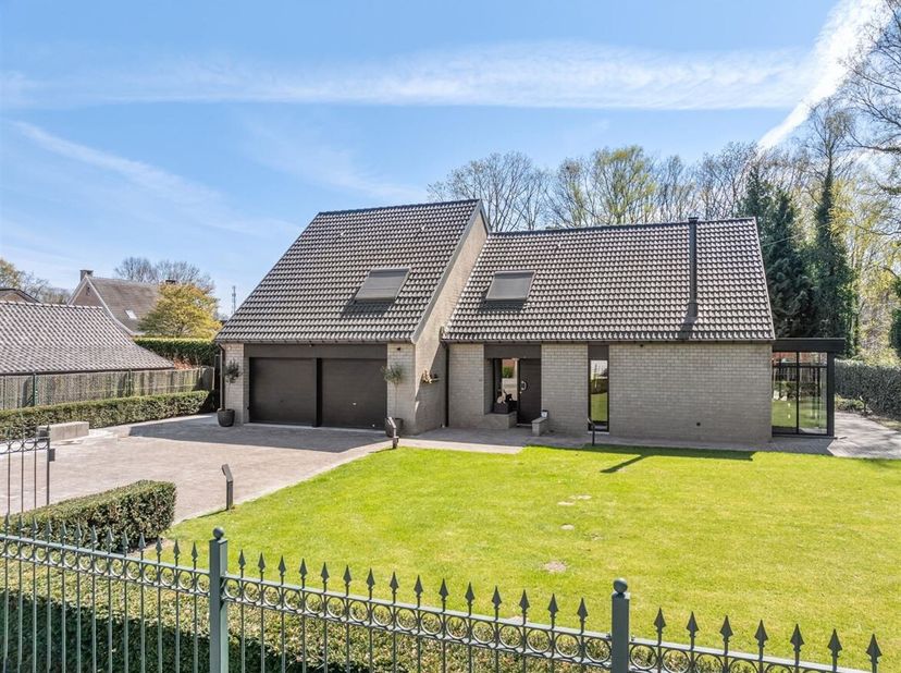 Bij binnenkomst verwelkomt een ruime inkomhal ons, met een gastentoilet en toegang tot de garage, bovenverdieping en leefruimte. De lichtrijke woonkam