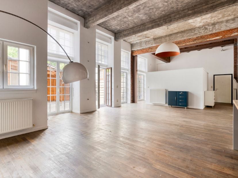 Ruim en lichtrijk loft appartement gelegen op het gelijkvloers in een verzorgd en rustig gebouw. De hoge plafonds en authentieke materialen vallen met