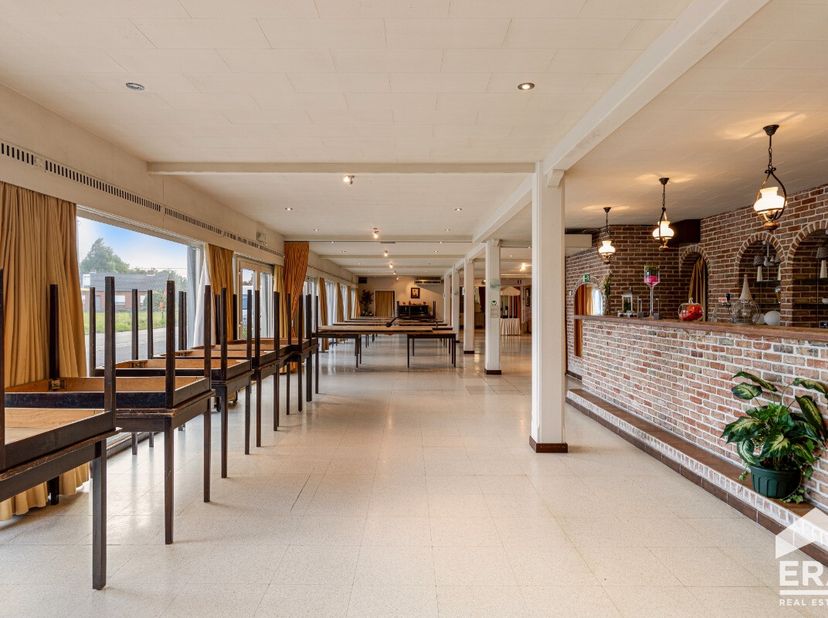 Groot polyvalent gebouw met een zaal (200 m²), woongelegenheid en loods/garage op een totale oppervlakte van 1.384 m²Dit op te frissen gebouw biedt ze