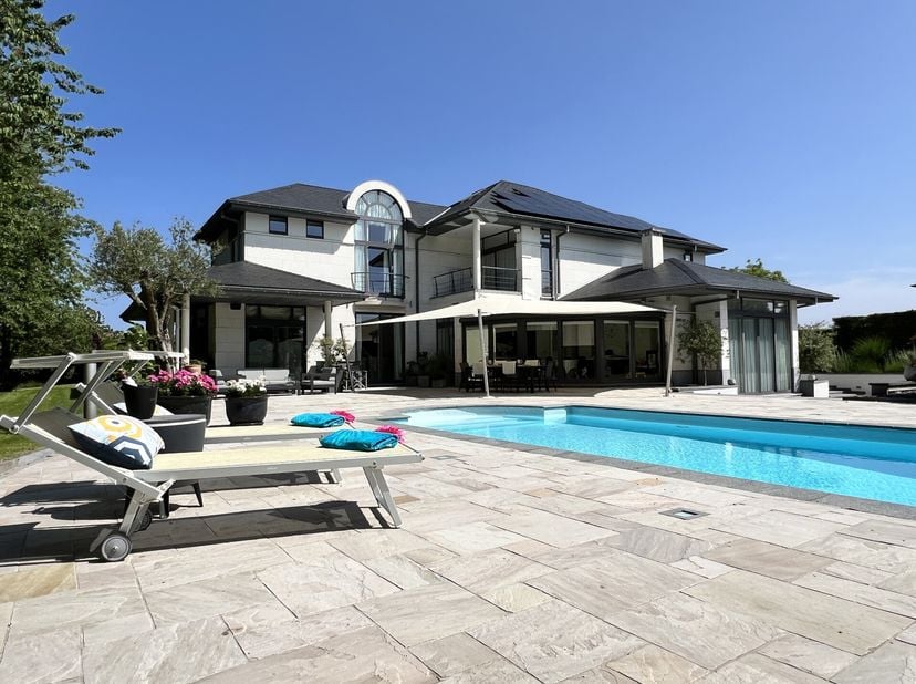 Ideaal gelegen dichtbij Joli-Bois, rust deze elegante en belichte villa uit 2008 met een bewoonbare oppervlakte van ± 443 m² (± 670 m² gebouwd) op een