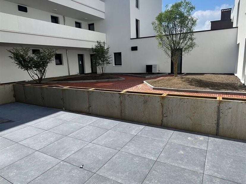 Dit laatste gelijkvloers appartement van wel 143,45 m² geeft uit op de prachtige binnentuin (nu net aangeplant) van het indrukwekkende project &quot;De Tan