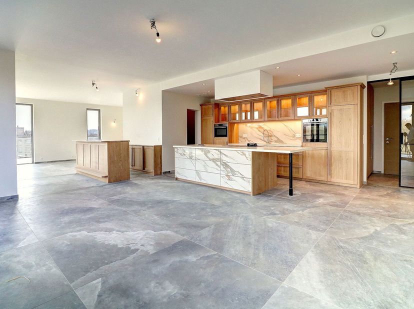 Volledig gerenoveerde penthouse bestaande uit:&lt;br /&gt;
- Inkomhal +- 5 m² met gepantserde deur&lt;br /&gt;
- Living met Amerikaanse keuken +- 86,5 m² met ruim