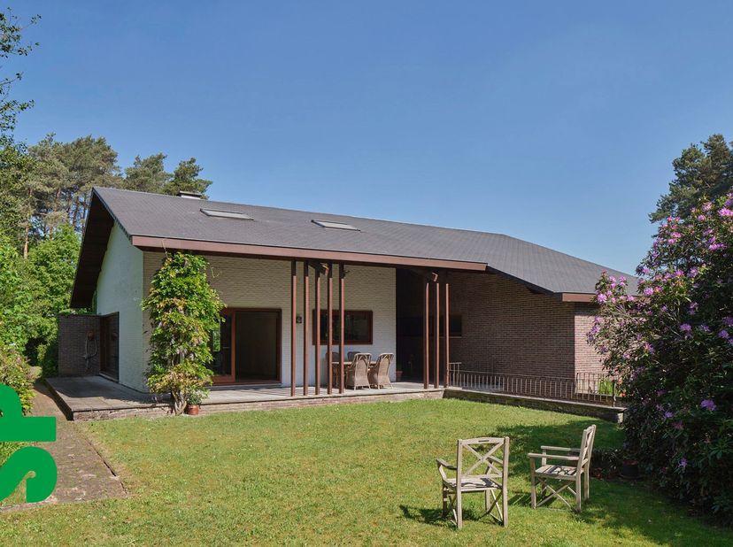 Verscholen in een uitzonderlijk groen en bosrijk decor ontvouwt deze karaktervolle villa van architect Bob Carpentier zich als een discreet modernisti