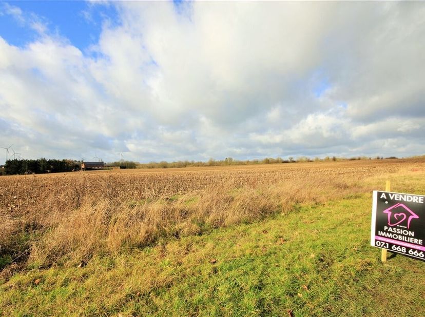 Terrain à bâtir dune superficie denviron 9 ares 77ca avec une longueur à rue de 16,4 m de façade pour une profondeur avoisinant les 50,9m. Le terrain