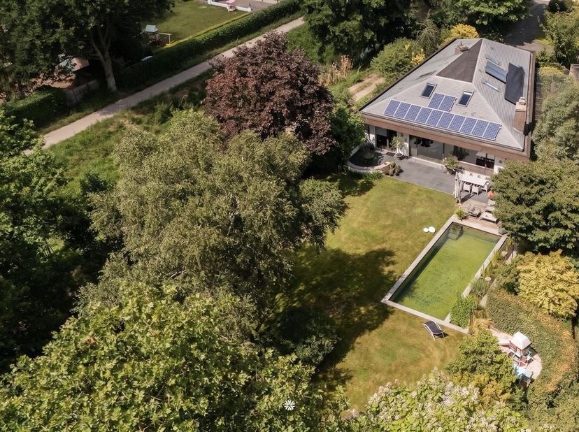 Verscholen in tweede bouwlijn, omgeven door groen en uitgestrekte velden, bevindt zich deze verrassende, modernistische woning nabij het centrum van S