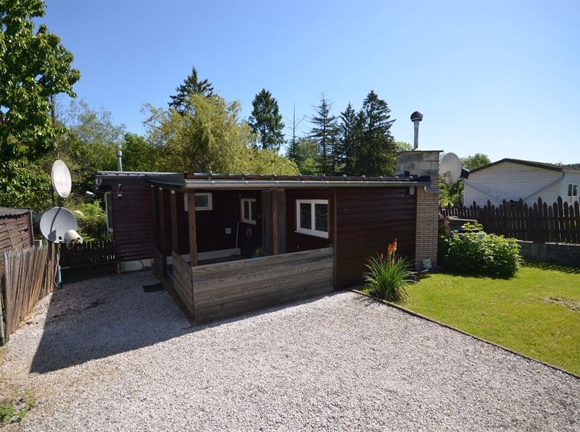 Charmante, met hout beklede woonwagen van ongeveer 37 m² in chaletstijl, in uitstekende staat, met bijgebouwen, gelegen in het aangename domein Caillo