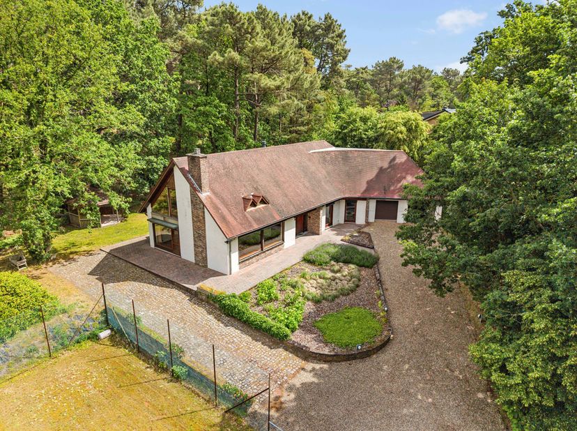 Cette spacieuse maison familiale est située dans un environnement boisé. La propriété offre beaucoup d'espace à l'intérieur et à l'extérieur avec ses