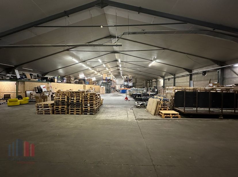 Praktische open opslagruimte van +/- 1.000 m² te huur. De gedeelde loods (25 x 40 m) is toegankelijk via een automatische sectionaal poort (4 m B x 4,