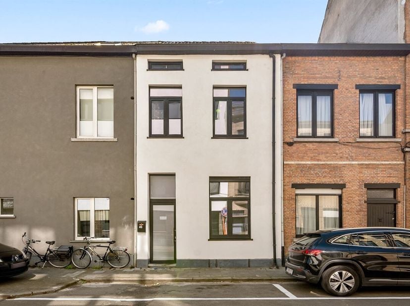 L'imposante façade de cette grande maison aux plafonds de même hauteur a été dotée d'un beau socle en pierre bleue et d'un enduit décoratif blanc, qui