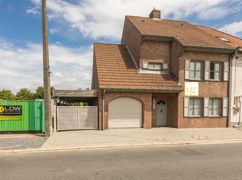 Heel ruime halfopen woning met garage, carport en gezellige tuin. De indeling is als volgt : Inkom met traphal en toilet. Vervolgens een ruime living