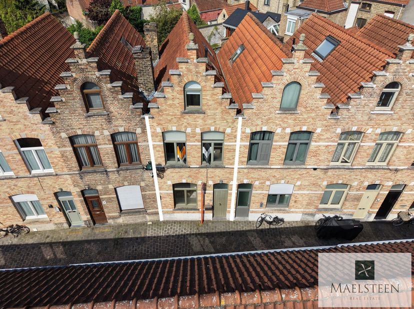 Dans une rue calme et pittoresque de Bruges, pavée de véritables galets, se trouve cette maison de ville prête à emménager avec une façade datant de 1