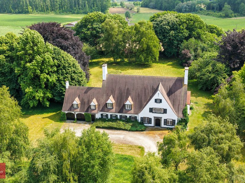 Villa gelegen op perceel van +/- 9.600m², bestaande uit inkomhal, bureel, living, eetplaats, keuken, bijkeuken (wasplaats), dagelijkse woonkamer (tv-k