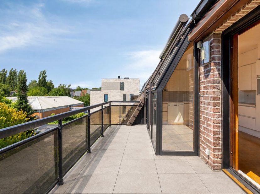 Op de derde en hoogste verdieping van een verzorgd gebouw (BJ 1991) langs de Brusselsesteenweg bevindt zich dit bijzonder ruime dakappartement met een