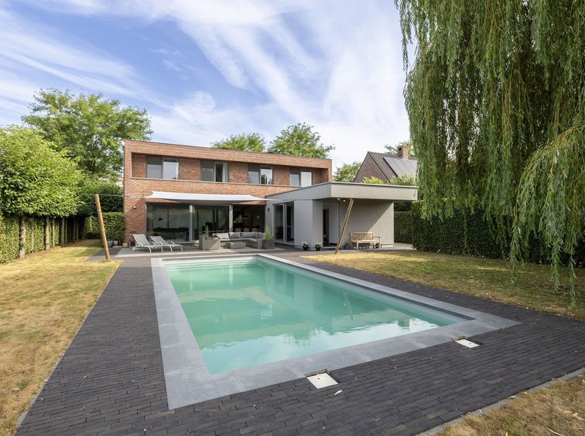 Deze moderne villa met 4slk en 2bdk, ruim zwembad en grote garage op een groen perceel van 1.282m² gelegen in een doodlopende straat op een steenworp