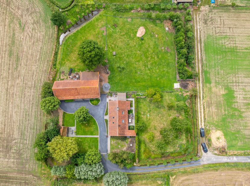 Via een lange oprijlaan, omgeven door groen en velden, bereik je deze prachtig gelegen hoeve in het landelijke Sint-Eloois-Winkel. Op een perceel van