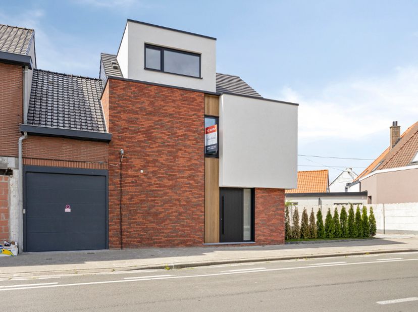 Deze woning onderscheidt zich moeiteloos in het straatbeeld. De combinatie van verfijnde gevelsteen, strakke witte crepi en zwarte platte dakpannen zo