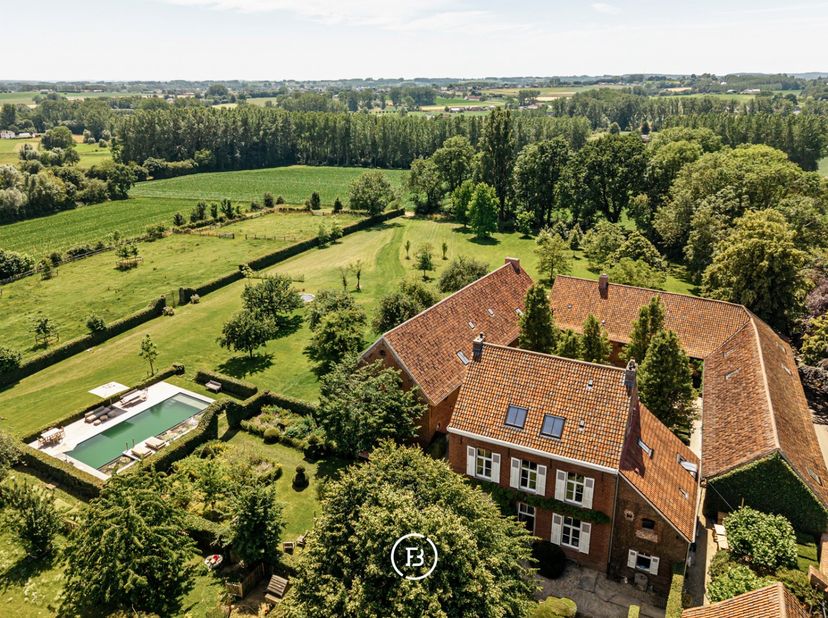 Midden in het glooiende landschap van de Vlaamse Ardennen bevindt zich deze uitzonderlijke vierkantshoeve op een privédomein van circa 4 hectare, rech