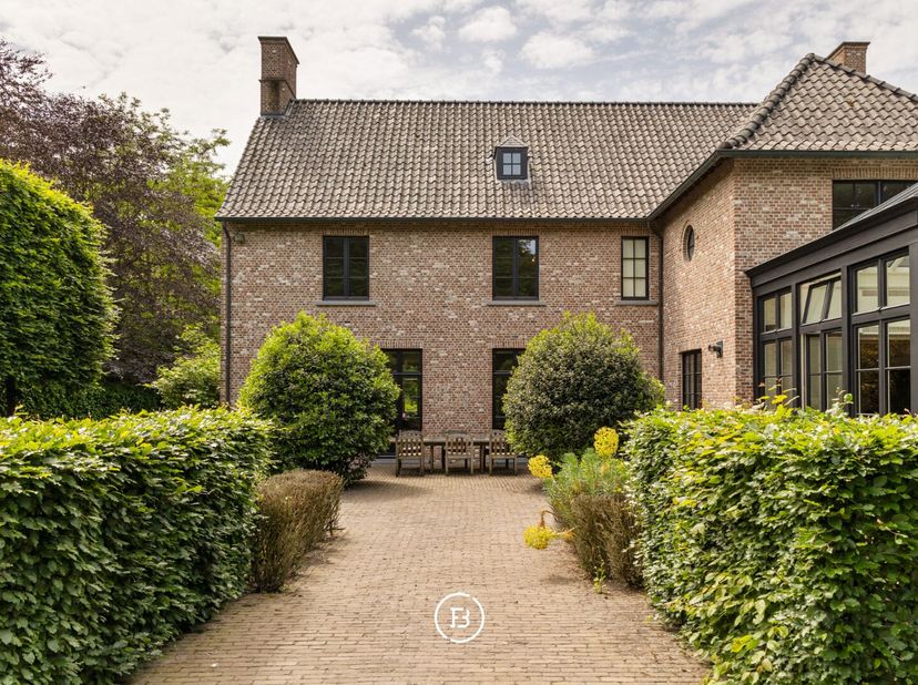 Een tijdloze villa in Genk, verscholen in het groen op een omheind perceel van 42 are. Achter de karaktervolle gevel in Vlaams kruisverband ontvouwt z