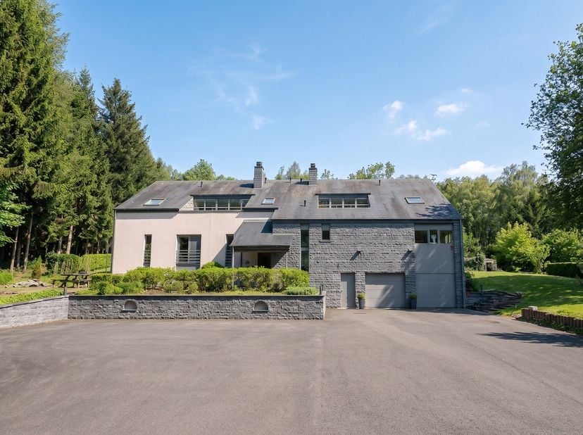 Gelegen nabij Houffalize, op een perceel van ongeveer 1,47 hectare met aangelegde tuin en privébos, biedt dit hedendaagse landgoed circa 700 m² bewoon