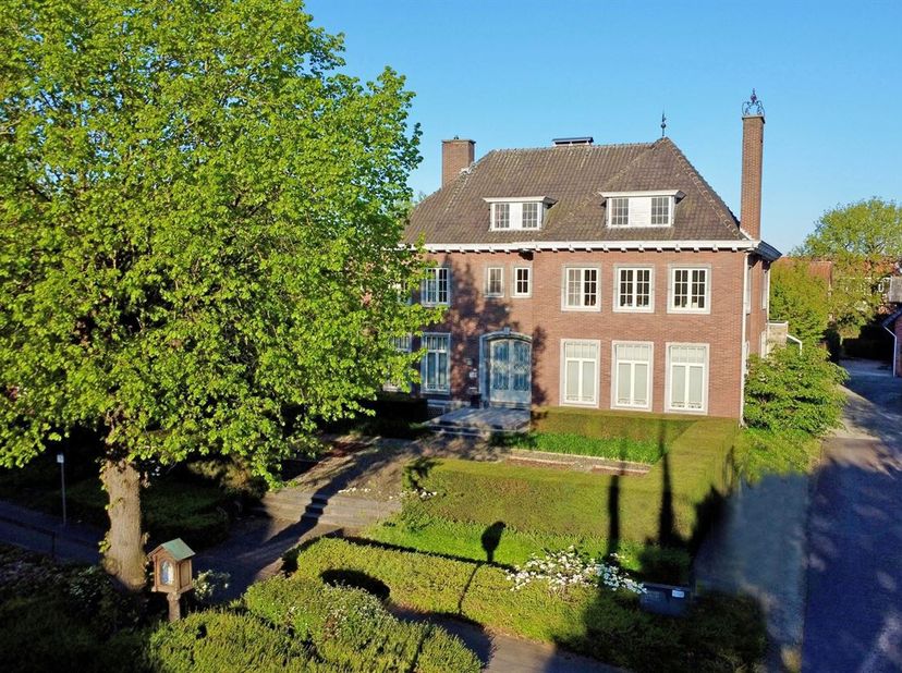 Via de inkomhal met gastentoilet betreden we enerzijds het leefgedeelte met een L-vormige woonkamer en eetkamer waar een open haard voor extra gezelli