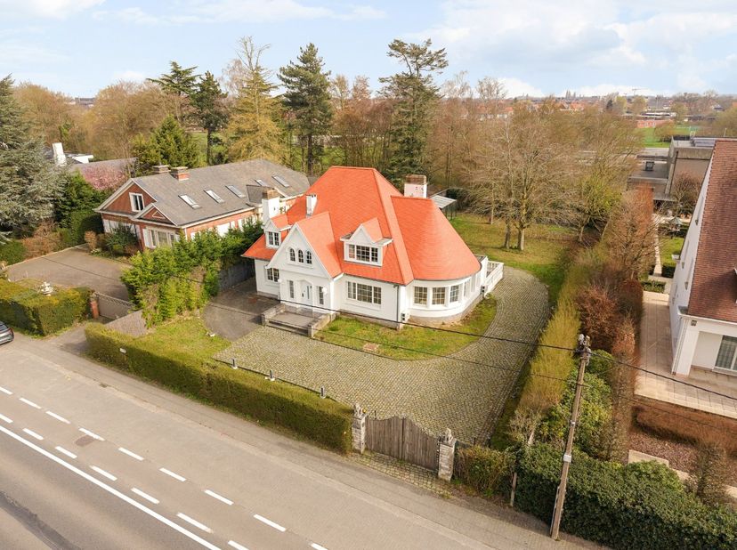 Bij het binnenkomen van deze klassieke villa, gebouwd in de Anglo-Normandische stijl, valt meteen de imposante en lichtrijke inkomhal op met mooie tra