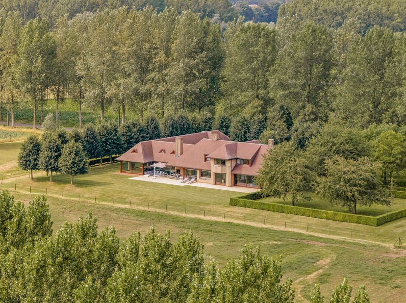 Te midden van het groen en de rust van Mendonk bevindt zich deze exclusieve villa op een domein van ca. 7 hectare, waar ruimte en natuur harmonieus sa