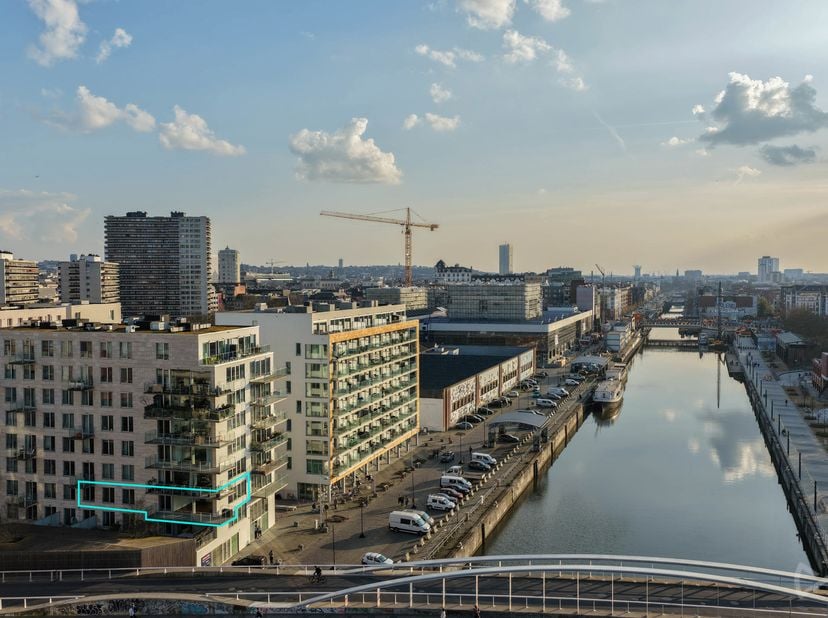 Op een uitstekende locatie aan het kanaal, recht tegenover Tour &amp;amp; Taxis, bevindt zich dit stijlvolle en recente appartement (bouwjaar 2018) op de