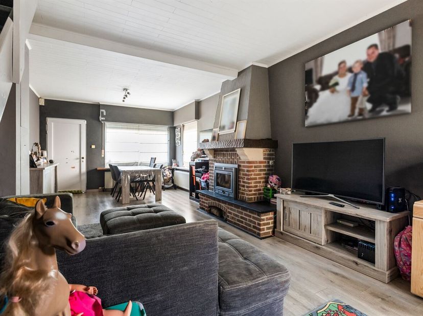 Half open bebouwing met 3 slaapkamer en zonnige tuin.<br />
We betreden de woonkamer. Deze geniet van een houtkachel en is ruim genoeg om eetplaats en