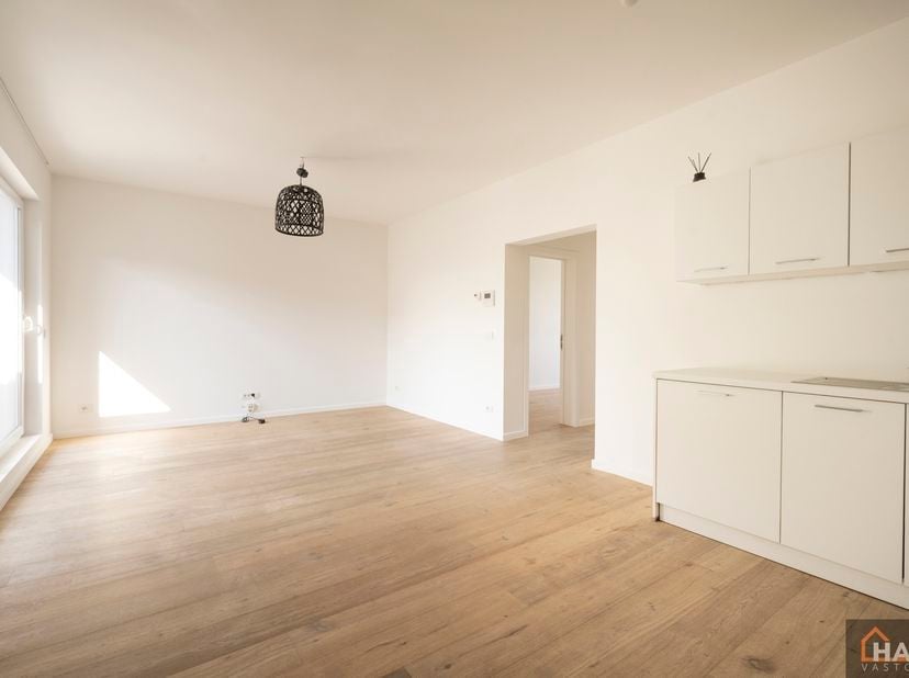 Inkomhal; leefruimte met open, geïnstalleerde keuken en schuifraam naar terras; 2 slaapkamers; badkamer met douche, toilet, lavabo in meubel en spiege
