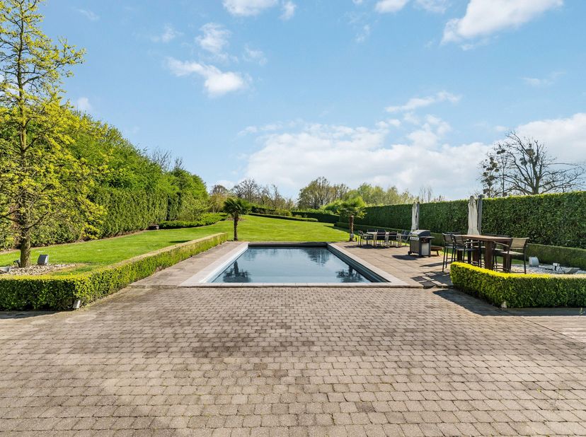Gelegen aan de Maastrichterstraat in Bilzen, biedt deze uitzonderlijke villa een oase van luxe en rust op een perceel van ca. 15.000 m². De ligging co
