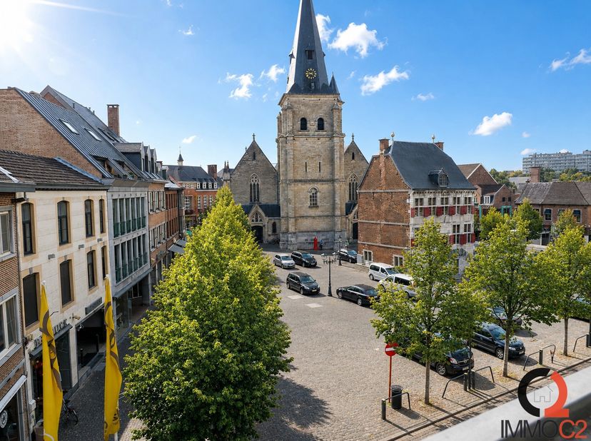 Ruim appartement (116 m²) met veel lichtinval gelegen in het centrum op de markt van Bilzen<br />
Indeling<br />
+ Inkomhal<br />
+ Grote woonkamer me