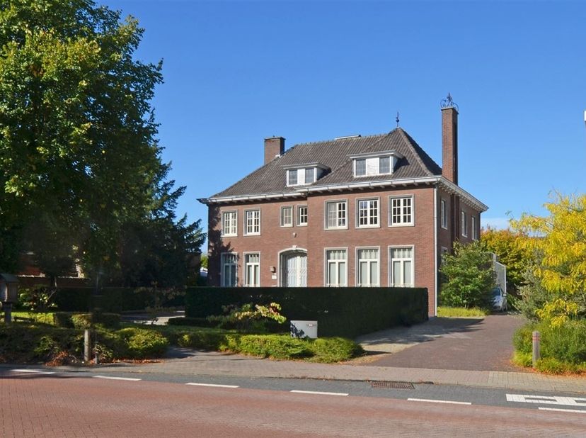 Via de inkomhal met gastentoilet betreden we enerzijds het leefgedeelte met een L-vormige woonkamer en eetkamer waar een open haard voor extra gezelli