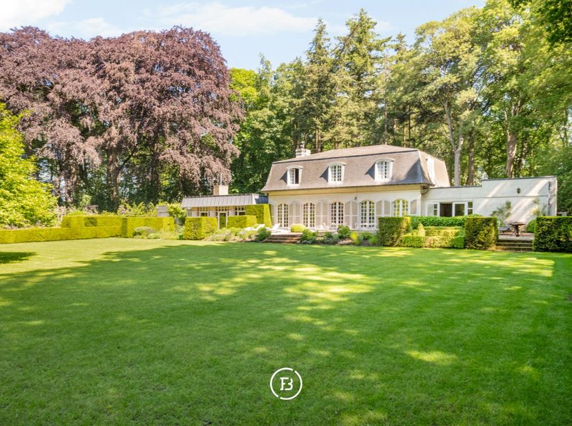 Verscholen in het groen en bereikbaar via een private dreef bevindt zich deze charmante villa in Franse stijl, subliem gelegen op een uitzonderlijk do