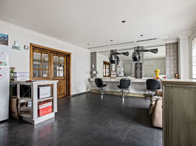 De woning beschikt over een bewoonbare oppervlakte van ca. 223 m². Vooraan bevindt zich een ruime polyvalente ruimte, momenteel ingericht als kappersr