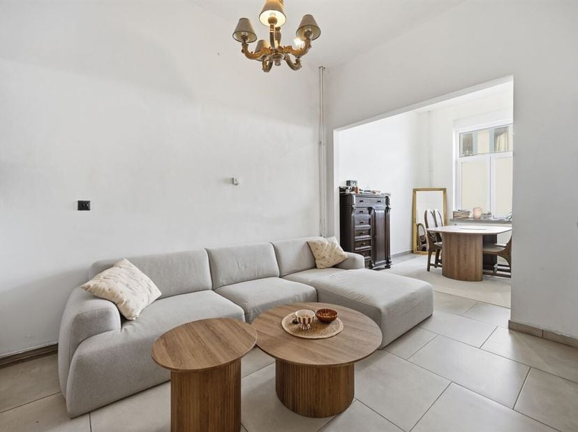 De statige voorgevel van deze hoge woning met dito plafonds, werd voorzien van een mooie plint in blauwe hardsteen en witte sierpleister, die goed con