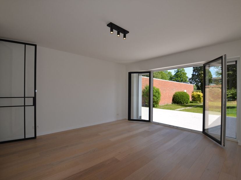 Prachtig gerenoveerd energiezuinig gelijkvloers appartement met garage, mooie tuin en ruim terras. Samenstelling: Inkom, ruime slaapkamer uitgevend op