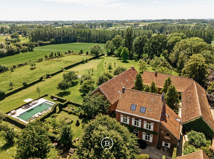 Midden in het glooiende landschap van de Vlaamse Ardennen bevindt zich deze uitzonderlijke vierkantshoeve op een privédomein van circa 4 hectare, rech
