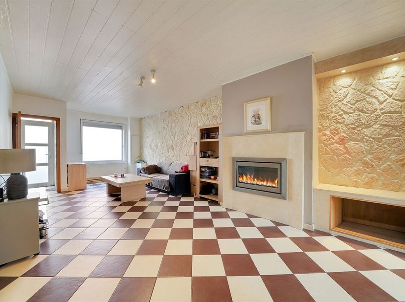 Ruim herenhuis met een hal die uitkomt op een woonkamer, een ingerichte keuken, een ruimte onder de trap die dienst doet als voorraadkamer, een verand