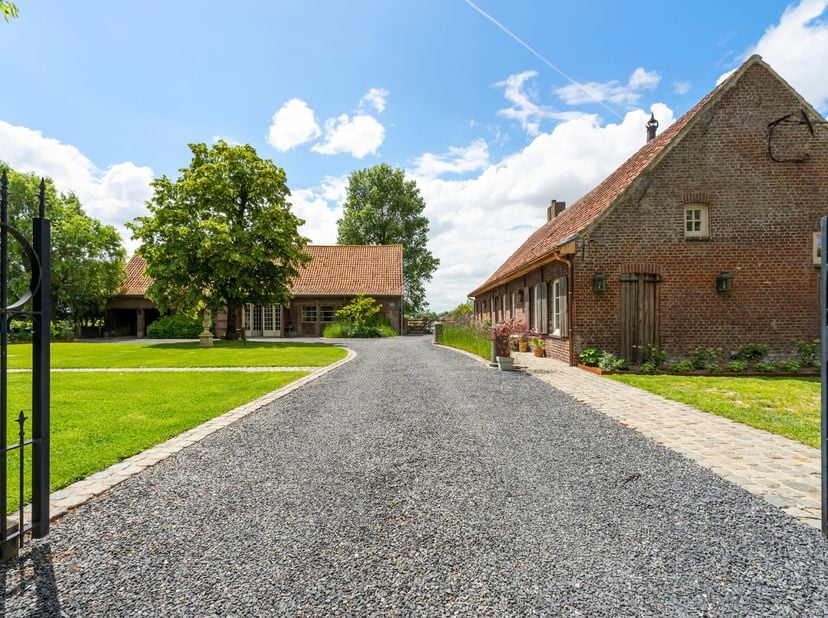 Via een lange oprijlaan, omgeven door groen en velden, bereik je deze prachtig gelegen hoeve in het landelijke Sint-Eloois-Winkel. Op een perceel van