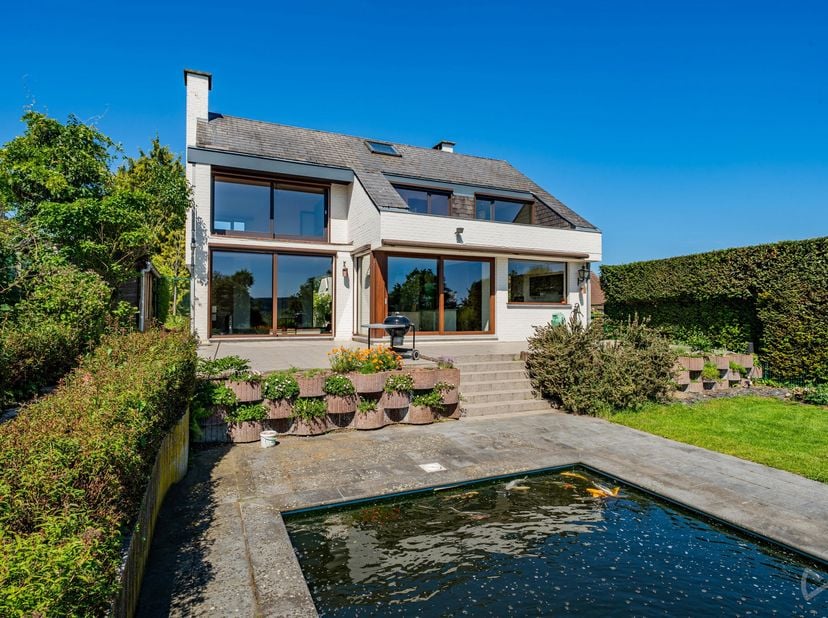 HULDENBERG – Nichée dans un environnement verdoyant et résidentiel, cette villa 4 façades de 310 m² (selon PEB) séduira les amateurs de lumière, de ca
