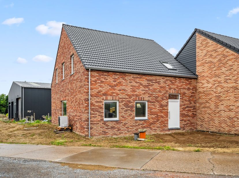 Het gelijkvloers van de woning bestaat uit een inkomhal die toegang biedt tot een apart toilet en de open leefruimte. De leefruimte is voorzien van ze